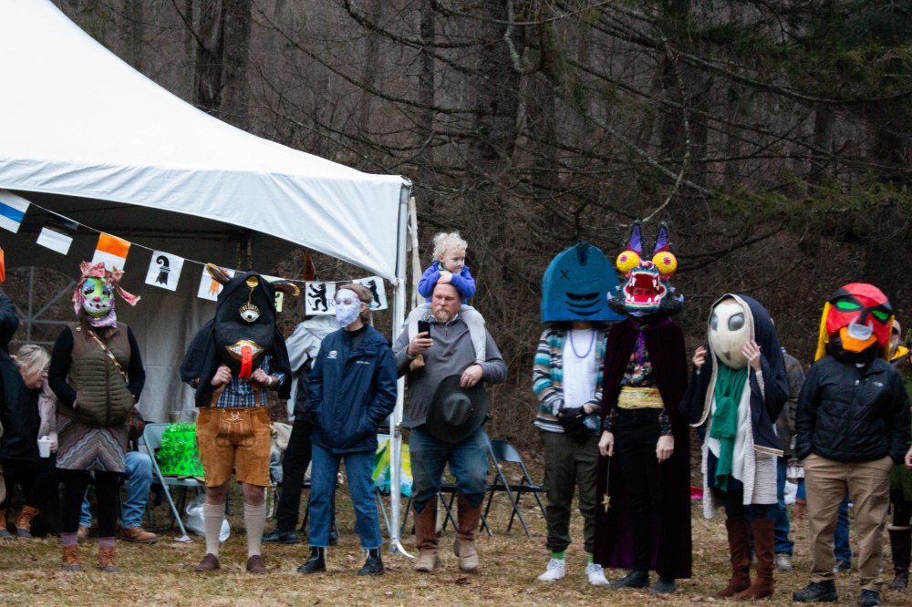 Masked people stand outside in front of a white tent.
