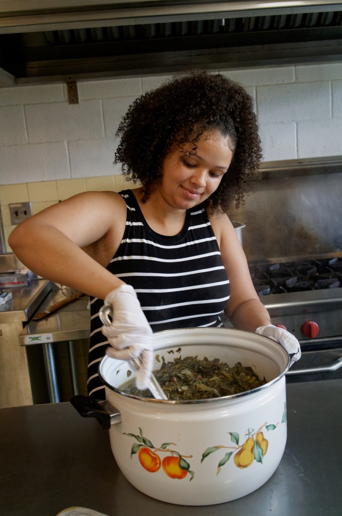 A young Black woman prepares greens.