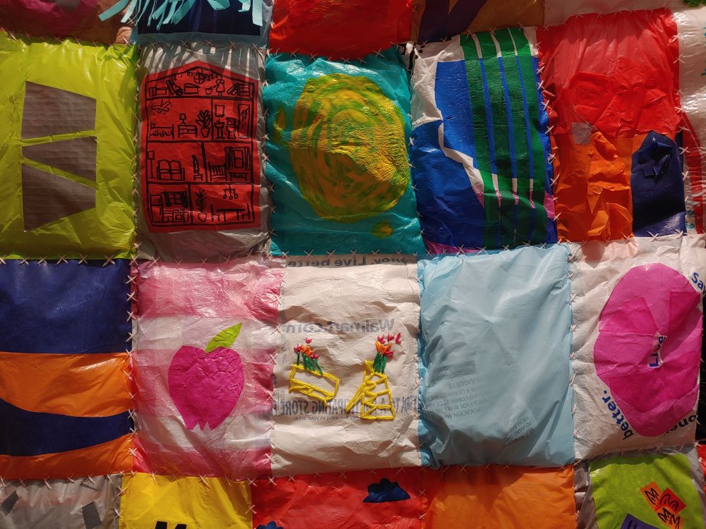 A plastic material quilt with vibrant and bright colors, and embroidery. Handstitched.