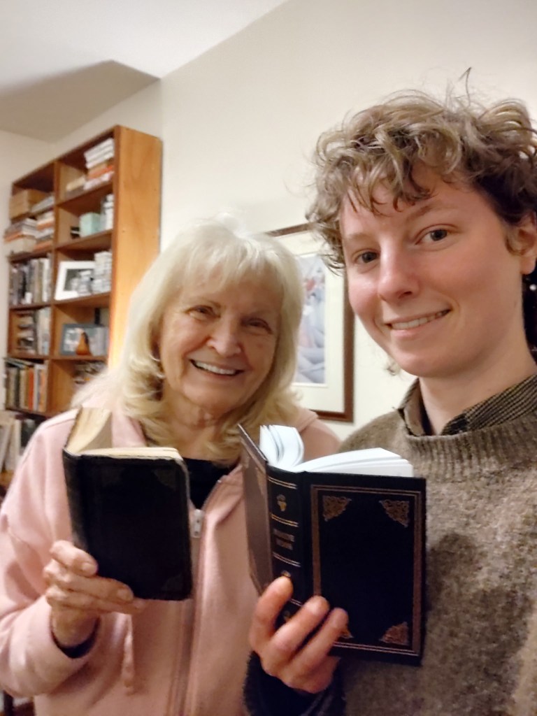 Two people smiling for a selfie and holding hymnals.