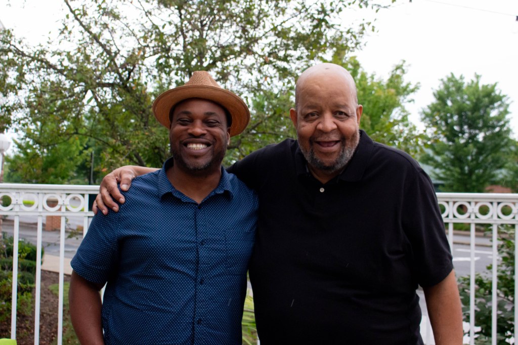 Two men standing beside each other smiling for a camera.